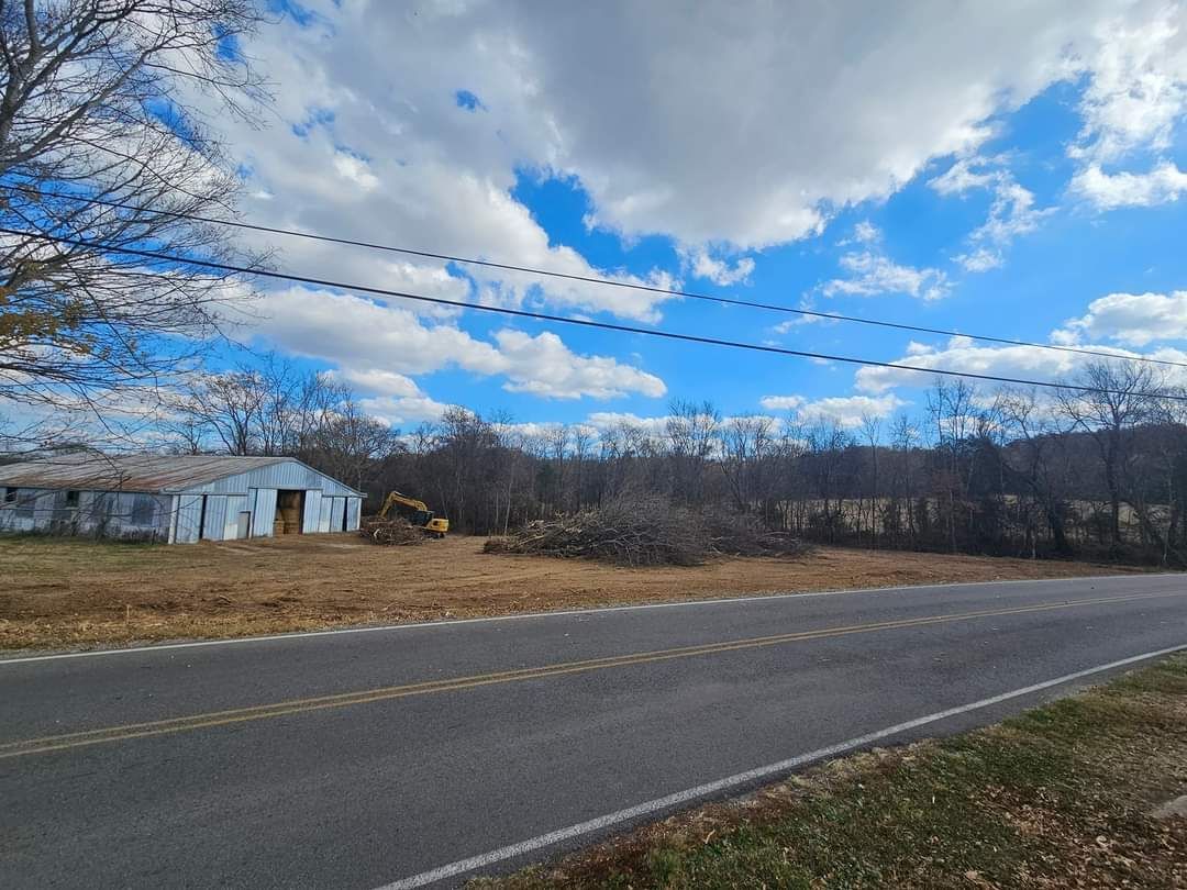 A road going through a field with a building in the background.
