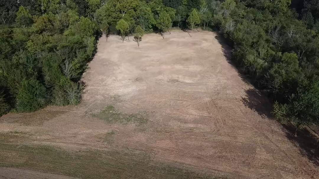 An aerial view of a field surrounded by trees.