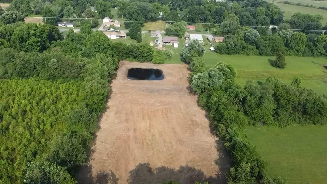 An aerial view of a dirt road surrounded by trees and grass.