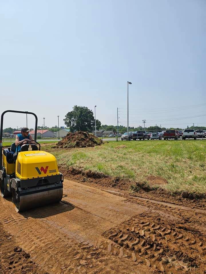 A man is driving a yellow roller on a dirt road.
