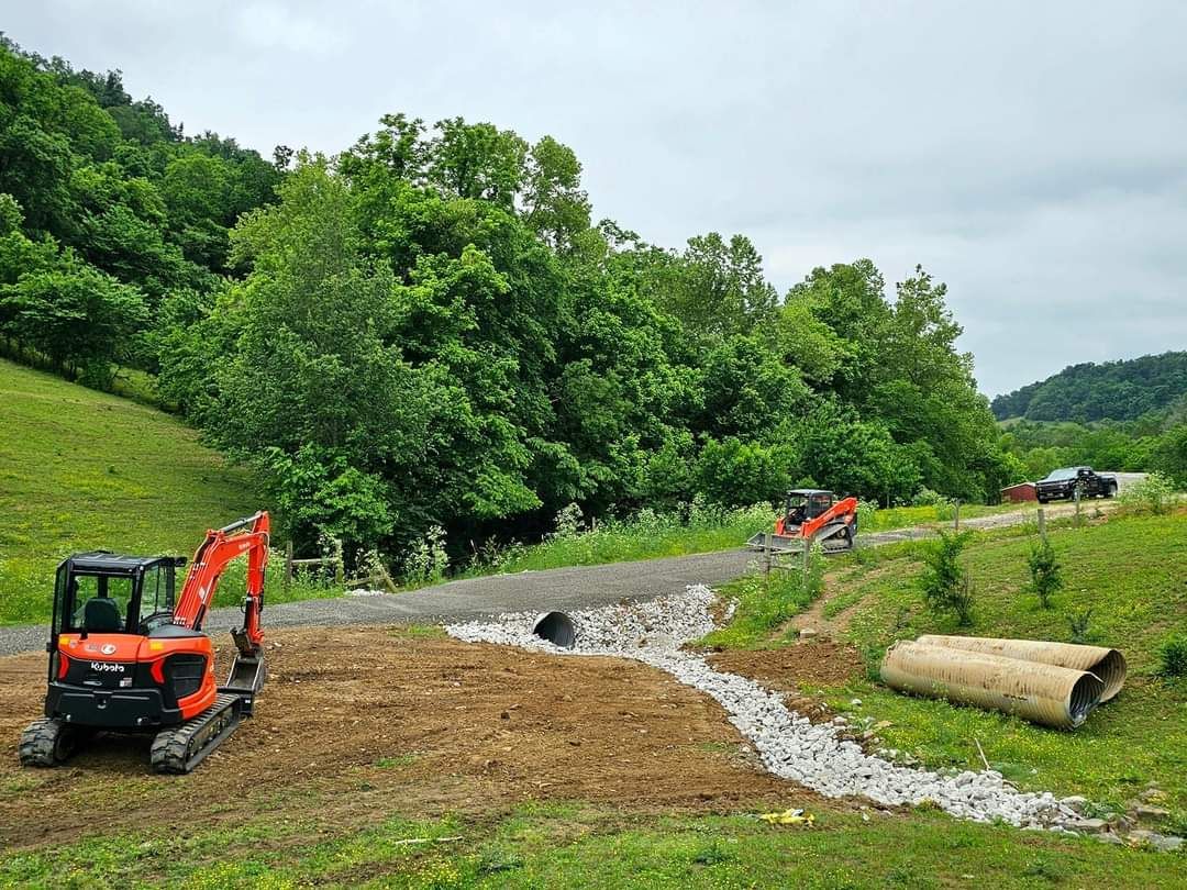 A red and black excavator is working on a dirt road.