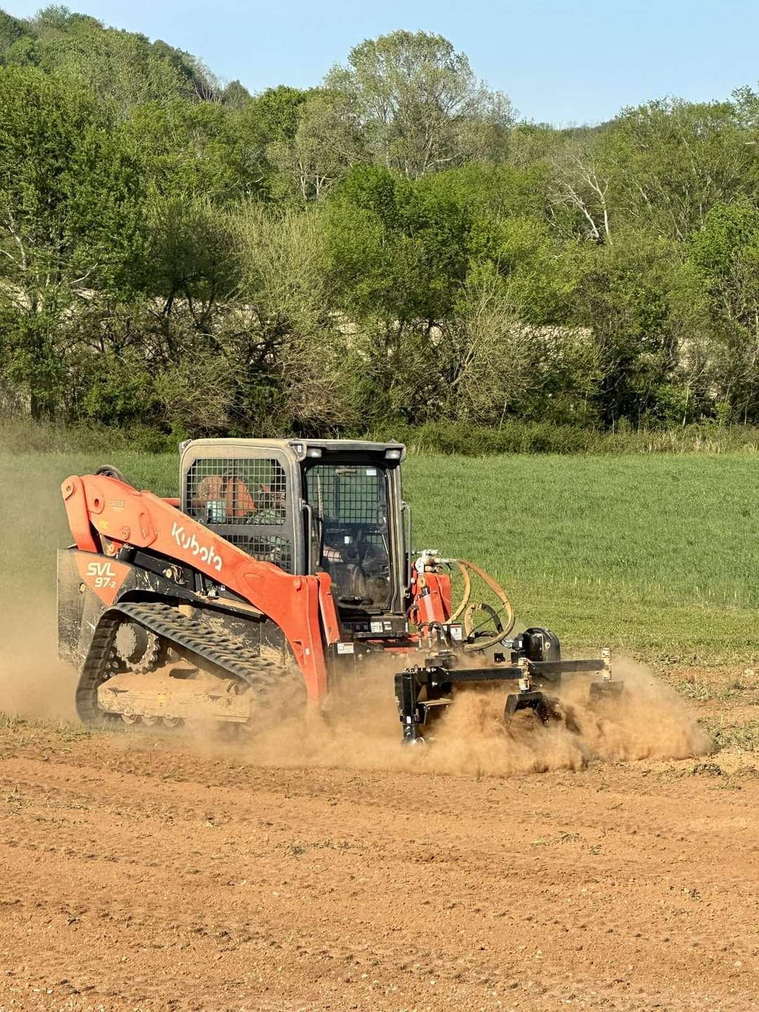 A tractor is driving through a dirt field.