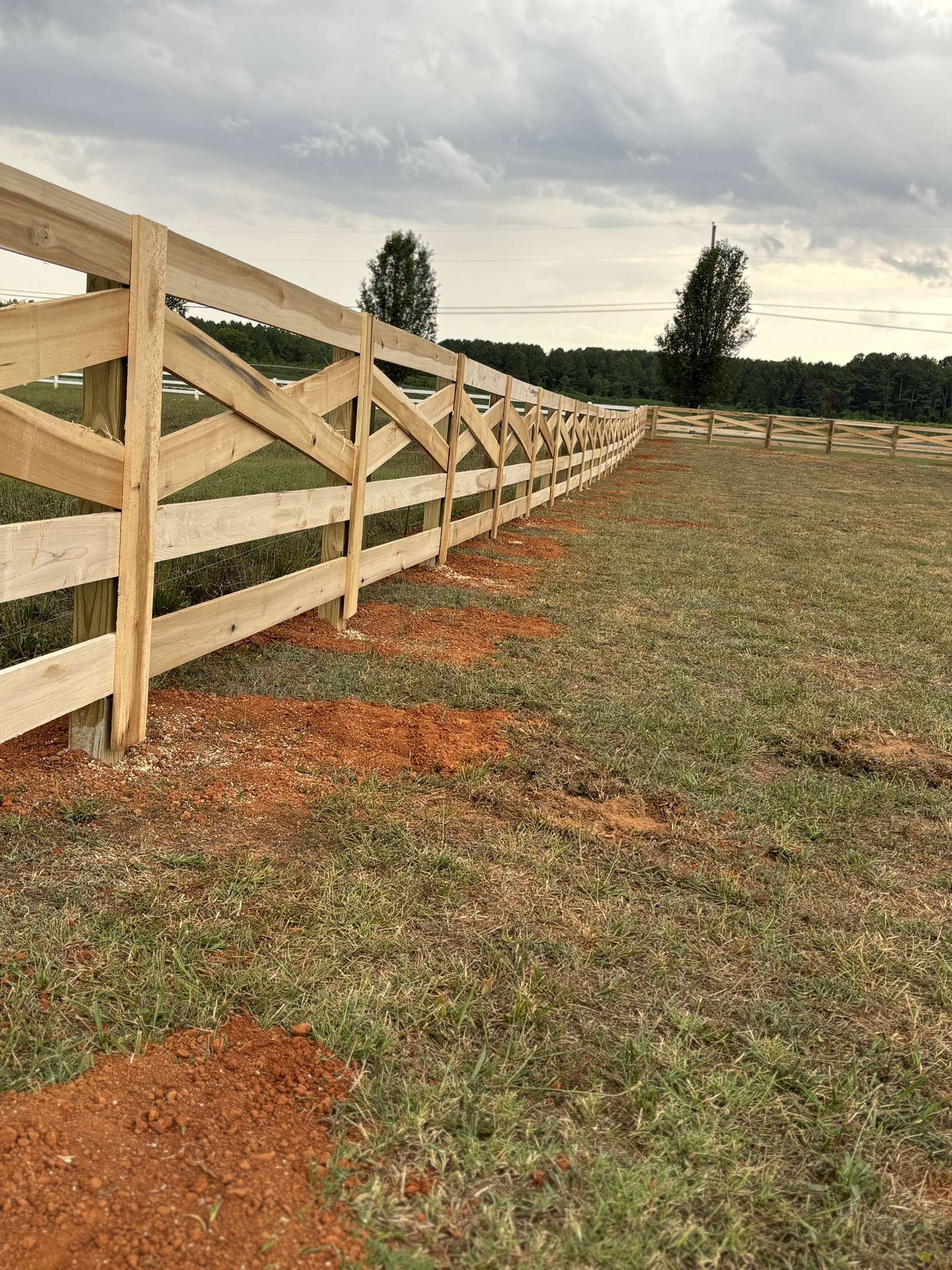 A wooden fence is in the middle of a grassy field.