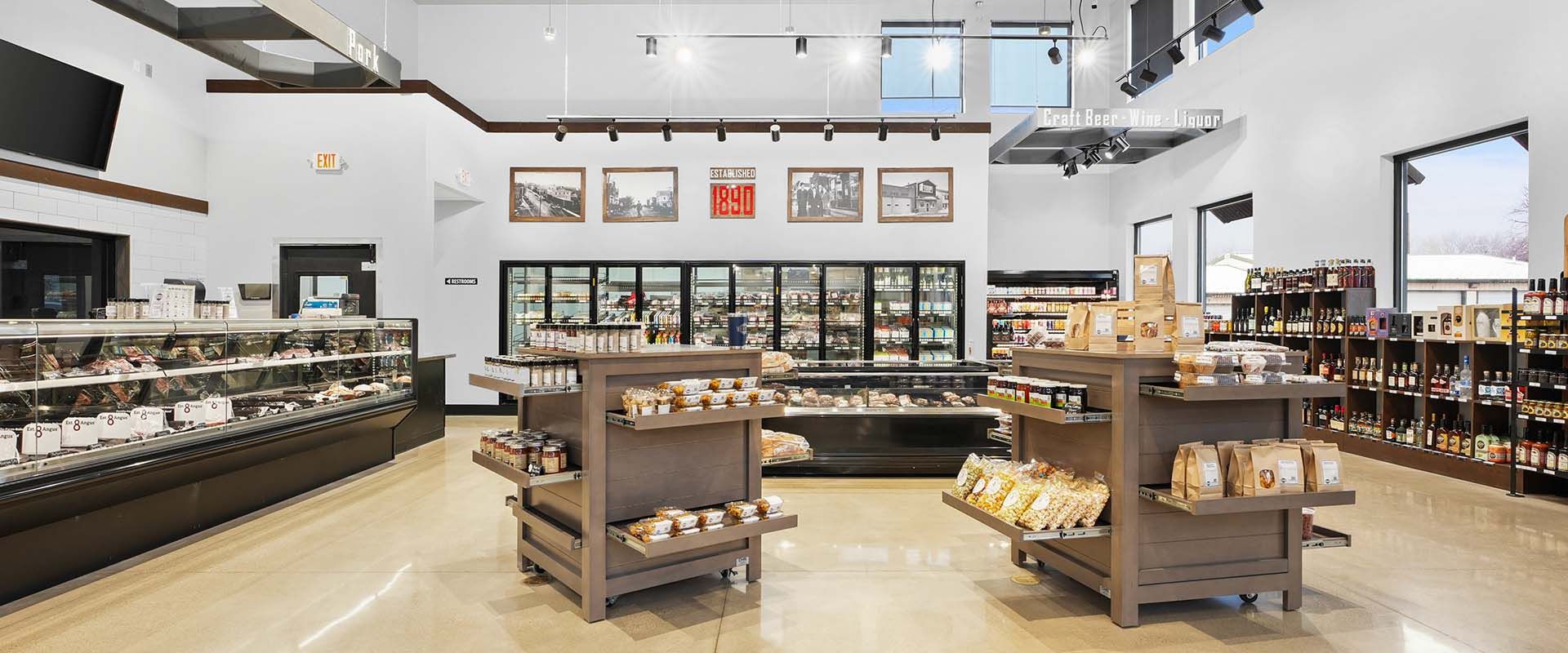 Bright, modern bakery interior with glass display cases, shelves of pastries, and hanging lights