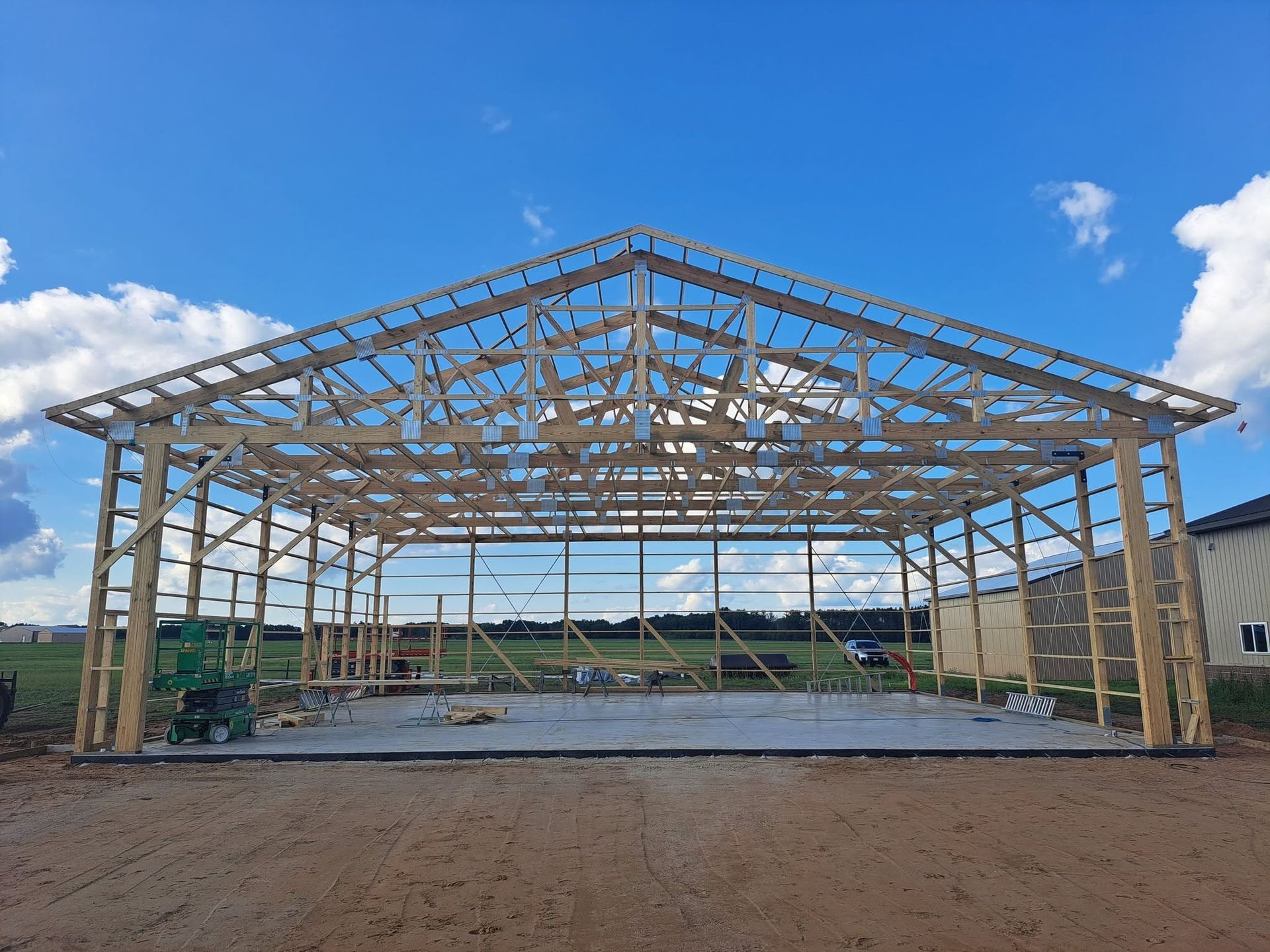 Steel-framed building under construction on a gravel site beneath a blue sky