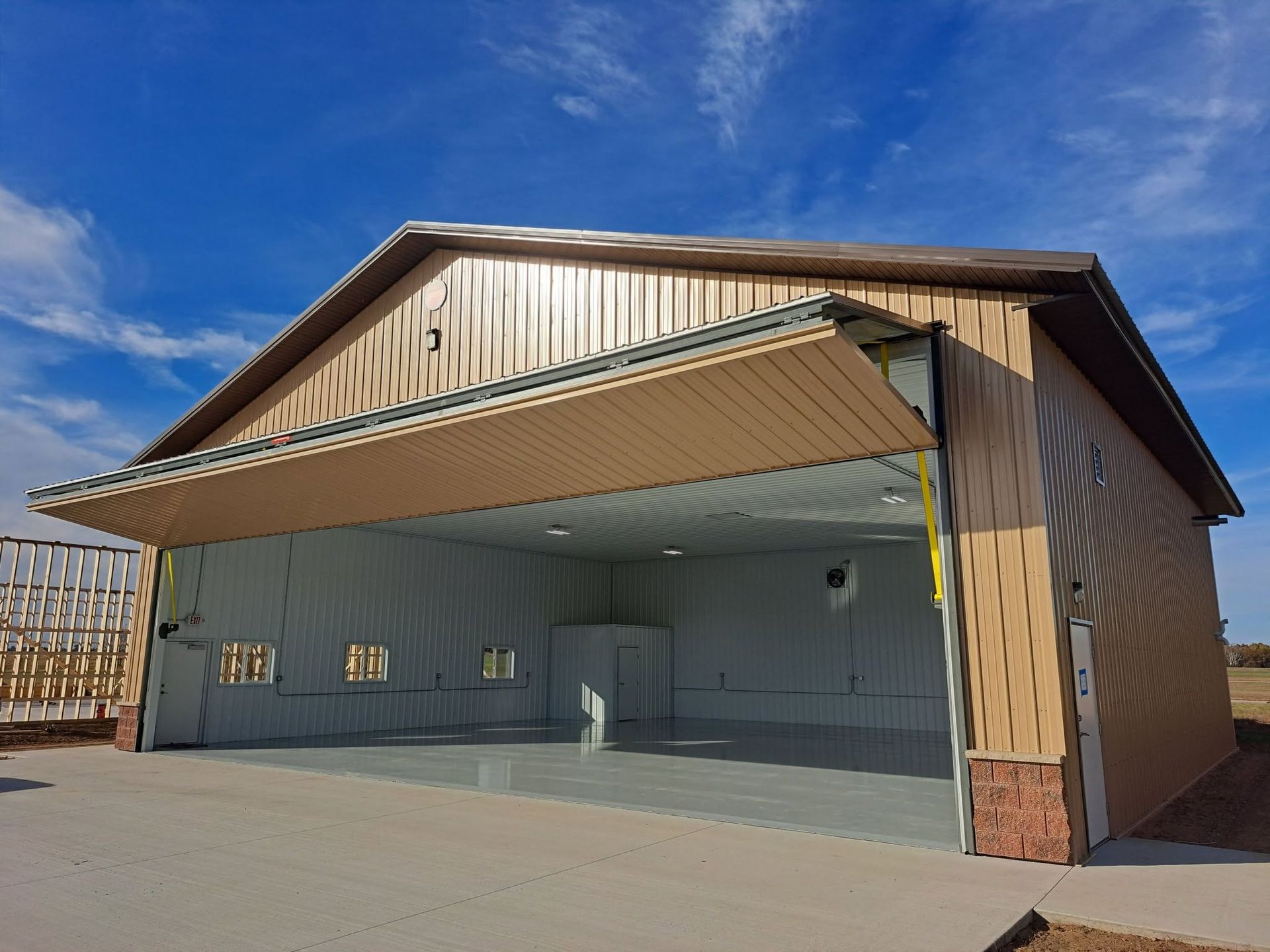 Open-sided pavilion with wood trim, a tan awning, and concrete floor under a blue sky