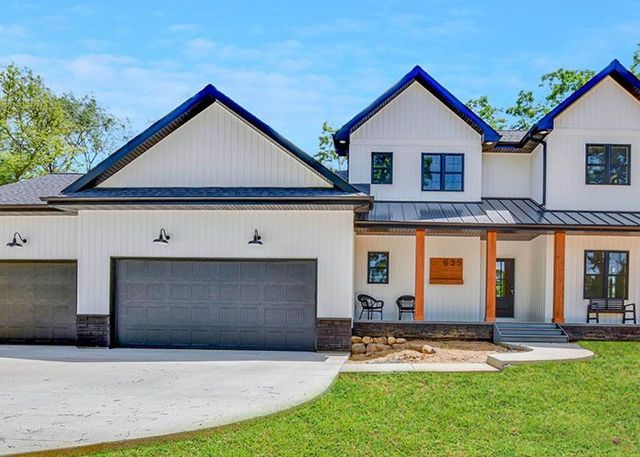 Modern white two-story house with gray garage doors, front porch, and green lawn