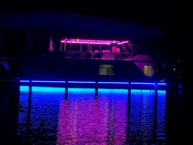 A boat is lit up with purple and blue lights on the water