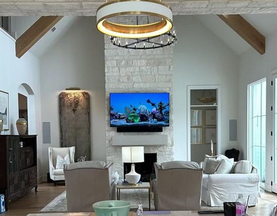 A living room with a couch, chairs, and a flat-screen tv on the wall.