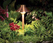 A copper pole light is sitting in the middle of a lush green garden