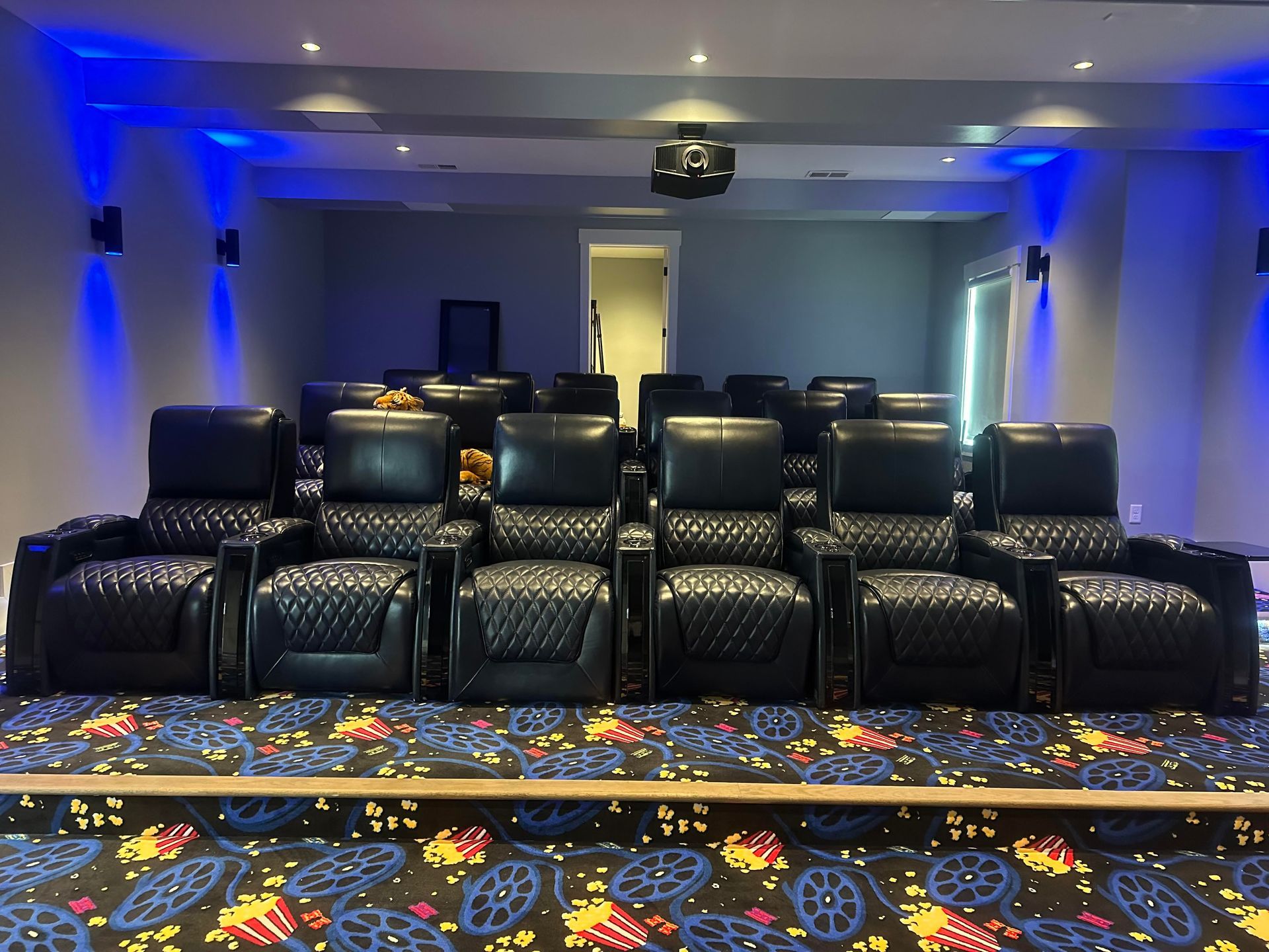 A home theater with black leather chairs and a projector screen.