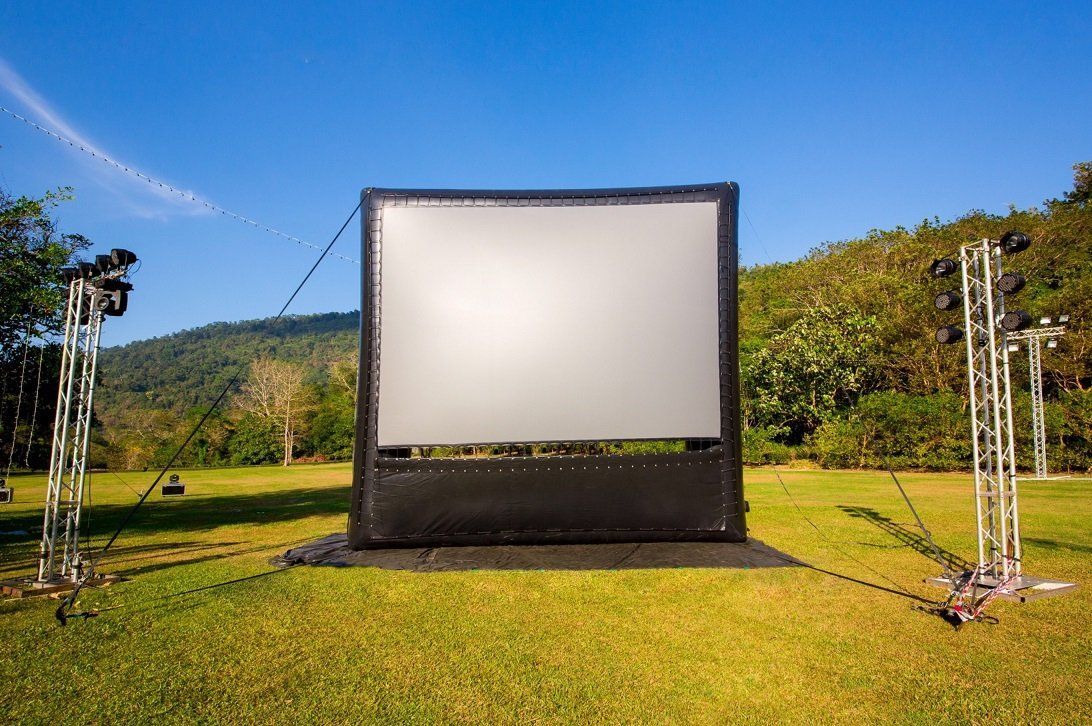 A large inflatable screen is sitting in the middle of a grassy field