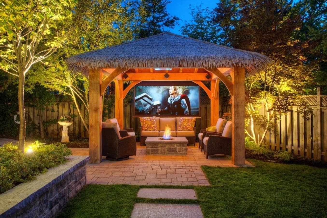 A gazebo with a projector screen in the backyard at night