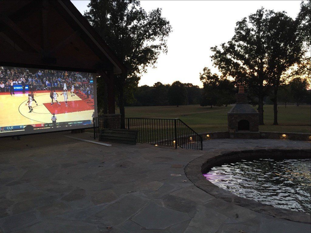 A basketball game is being played on a large screen outside