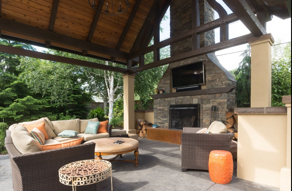 A patio with furniture and a fireplace under a canopy