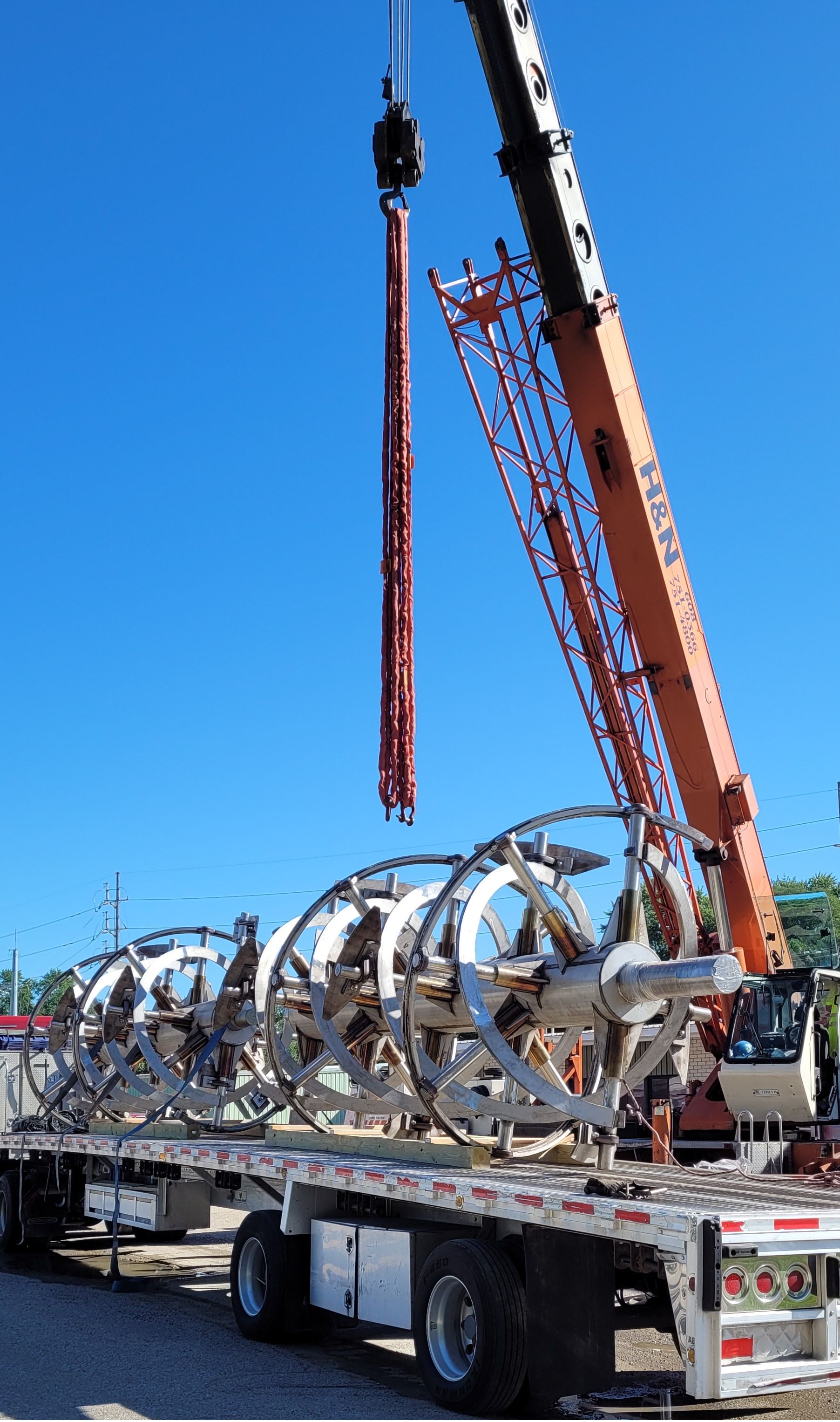 a large crane is lifting a large object from a flatbed truck .