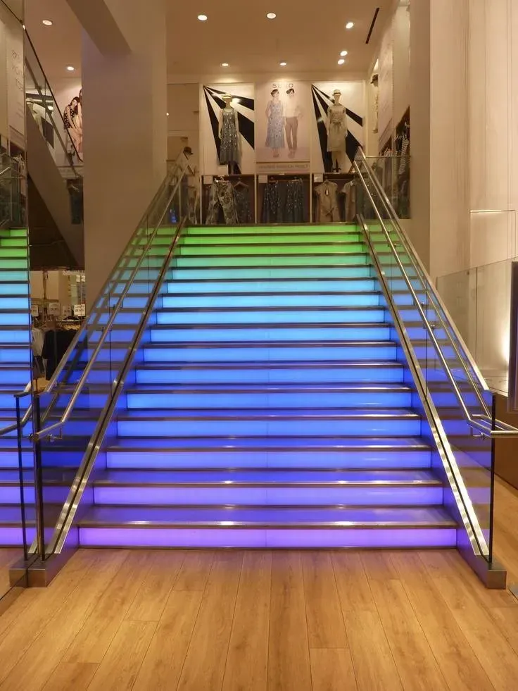 Illuminated staircase with blue and green steps in a modern indoor lobby