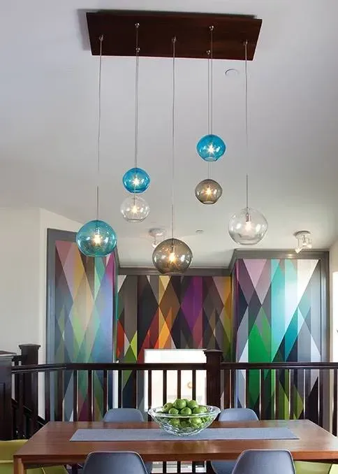 Modern dining room with colorful pendant lights and geometric wall art above a wooden table