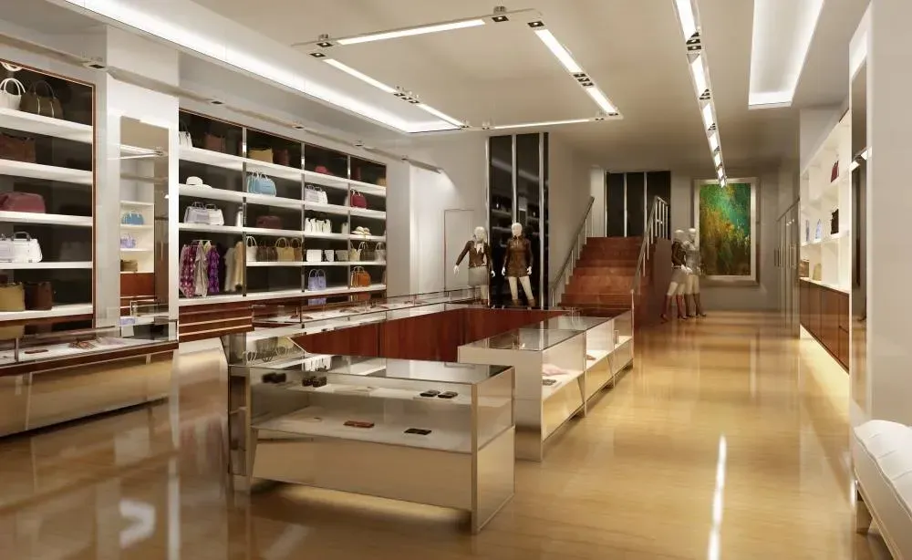 Modern boutique interior with glass display tables, wall shelves, and stairs in a polished wood-floored store