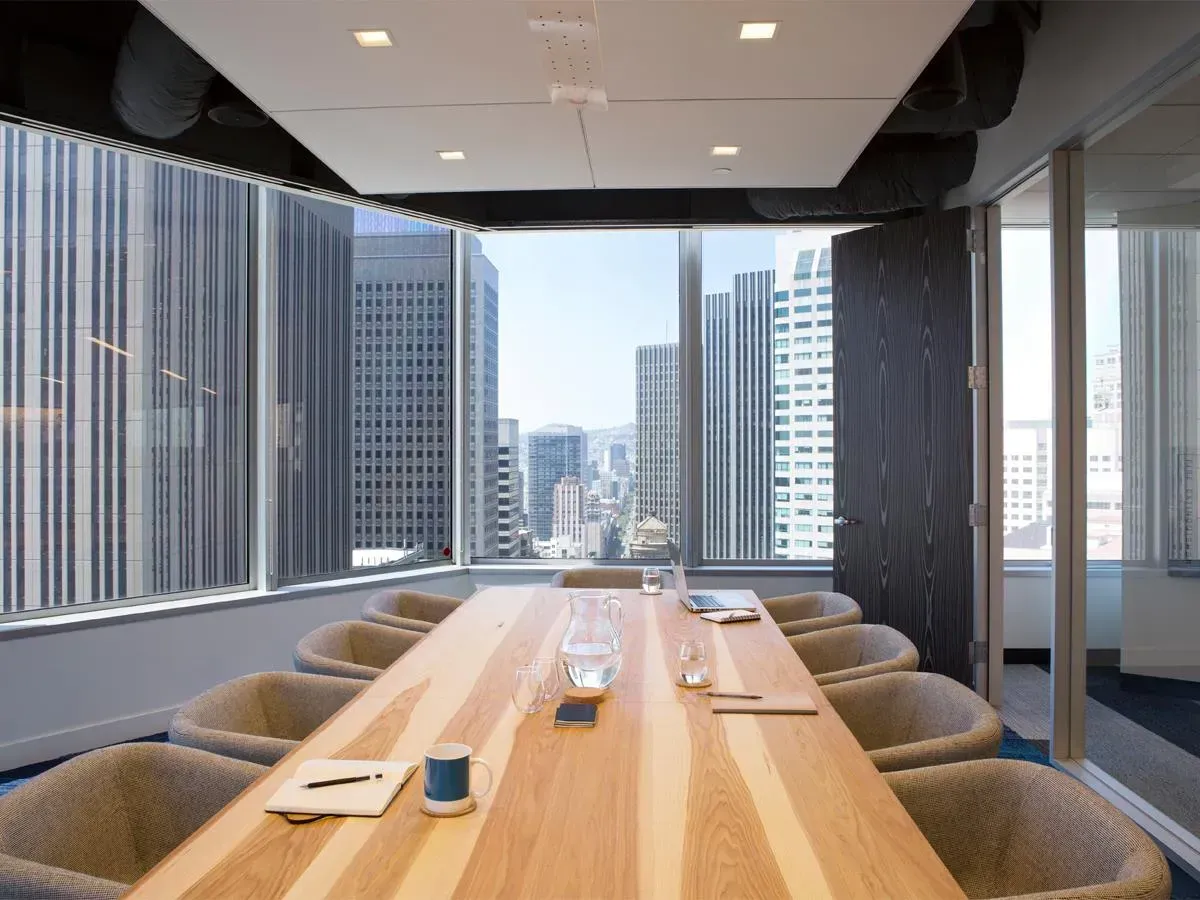 Modern conference room with long wooden table and city skyline view through large windows