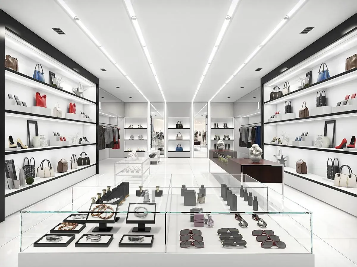 Bright white luxury boutique with handbags and accessories displayed on wall shelves and glass cases