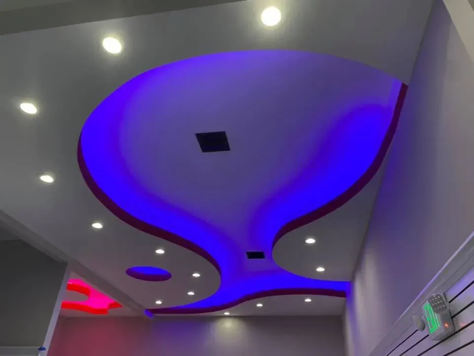 Ceiling with circular recessed lighting and purple-blue accent lights in a modern hallway