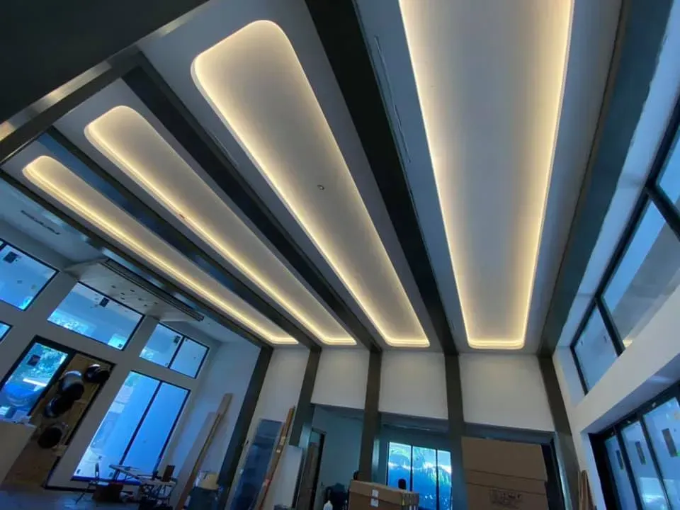 Modern interior with illuminated ceiling panels, glass walls, and blue-tinted windows