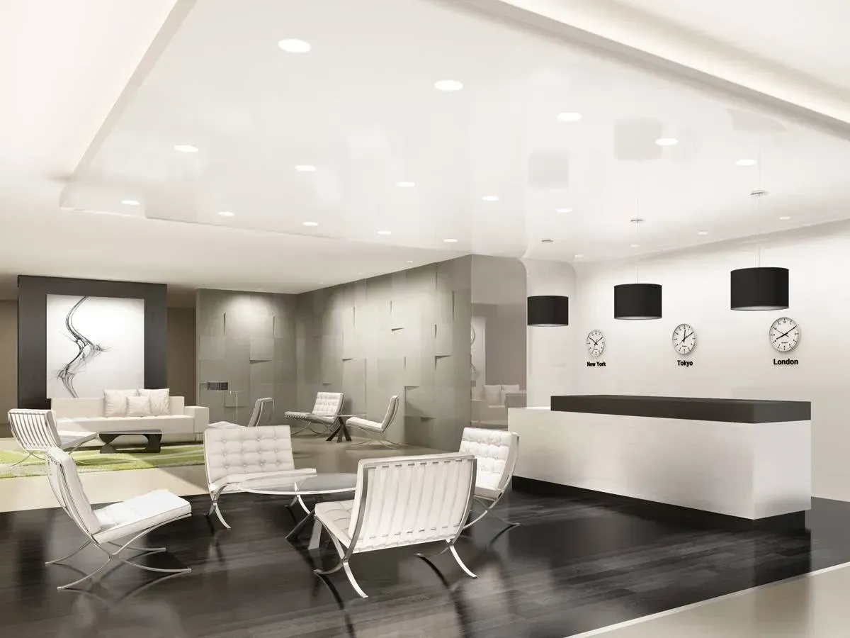 Modern minimalist lobby with white lounge chairs, dark flooring, and a sleek reception desk