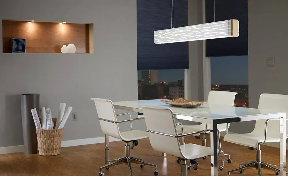 Modern dining room with white chairs, glass table, pendant light, and city view at night