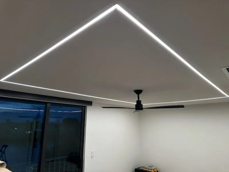 Bright white ceiling with LED strip lighting and a black ceiling fan in a modern room