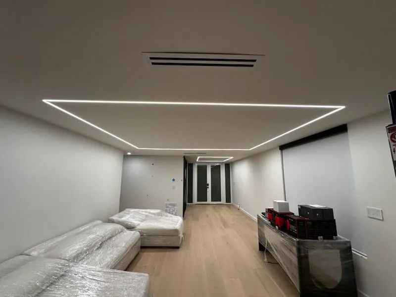 Minimalist living room with white sectional sofa, wood floor, and recessed LED ceiling lights