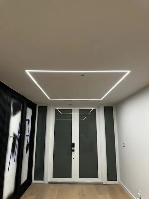 Modern hallway with a white ceiling light, gray walls, and frosted glass double doors