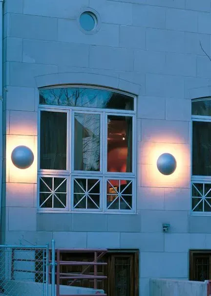 Blue-lit building facade with white windows and circular wall lights at dusk