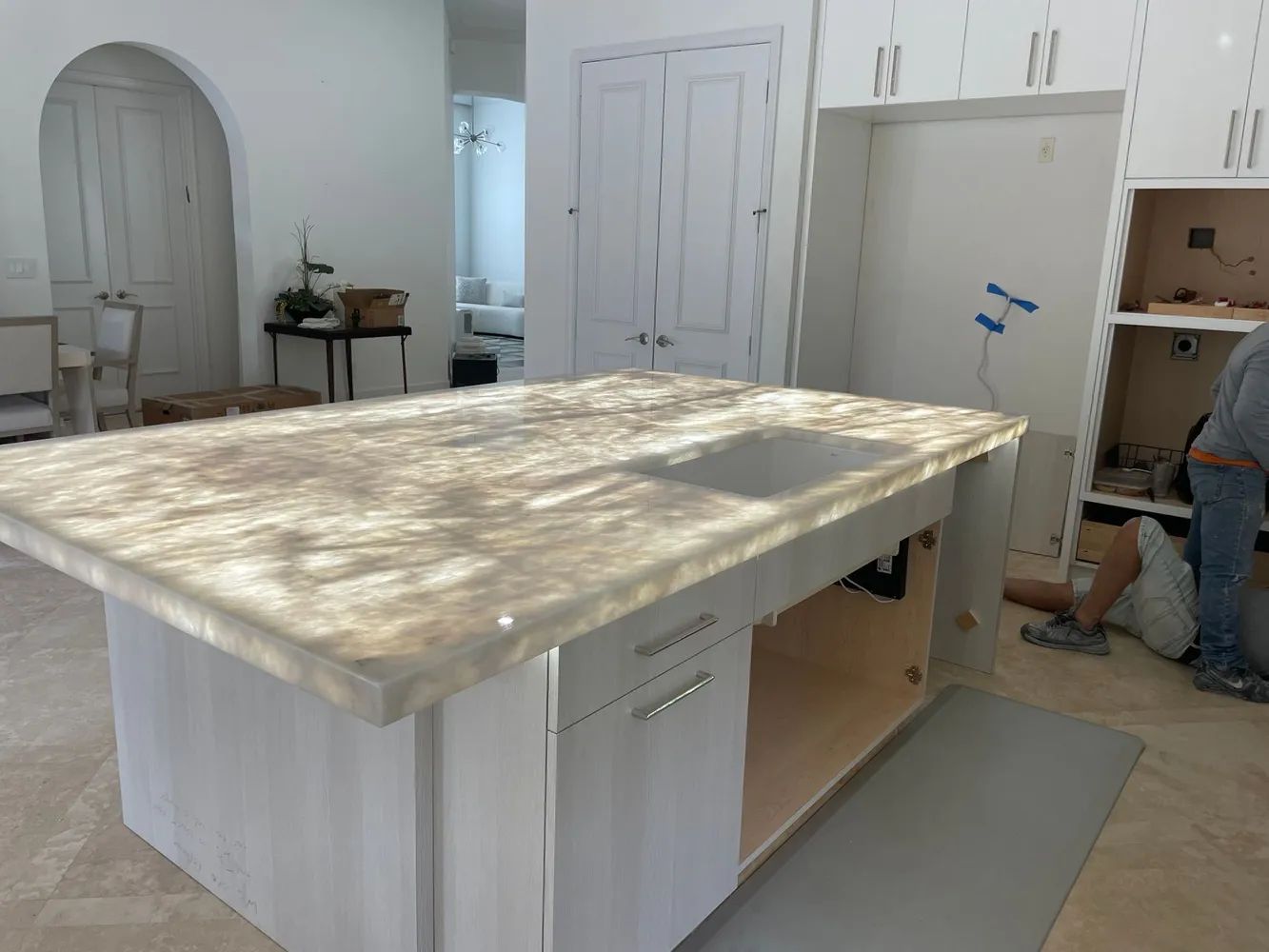 Kitchen island under construction in a bright room, with white cabinets and tools nearby.