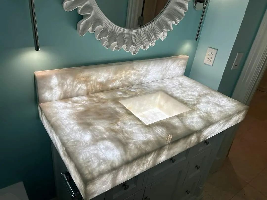 Marbled white bathroom vanity top with built-in sink and decorative mirror in a teal room