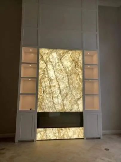 Tall illuminated marble wall panel flanked by lit cabinets in a modern interior