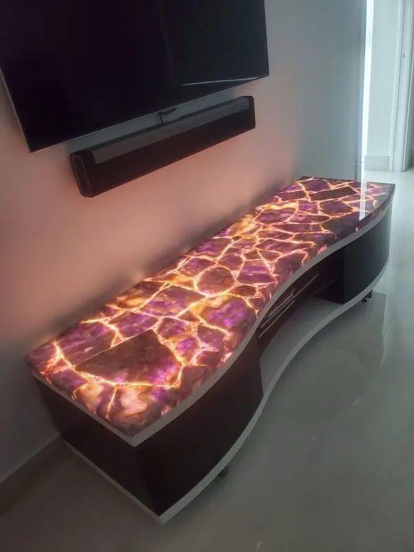 Glowing lava-pattern bench beneath a wall-mounted TV in a modern room