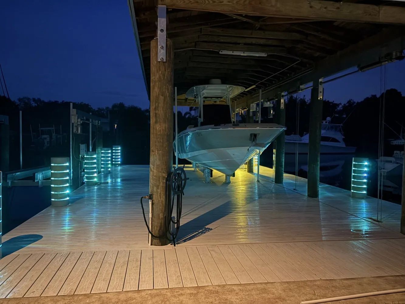 Nighttime poolside deck with glowing blue lights and a martini glass-shaped lounge chair under a covered patio
