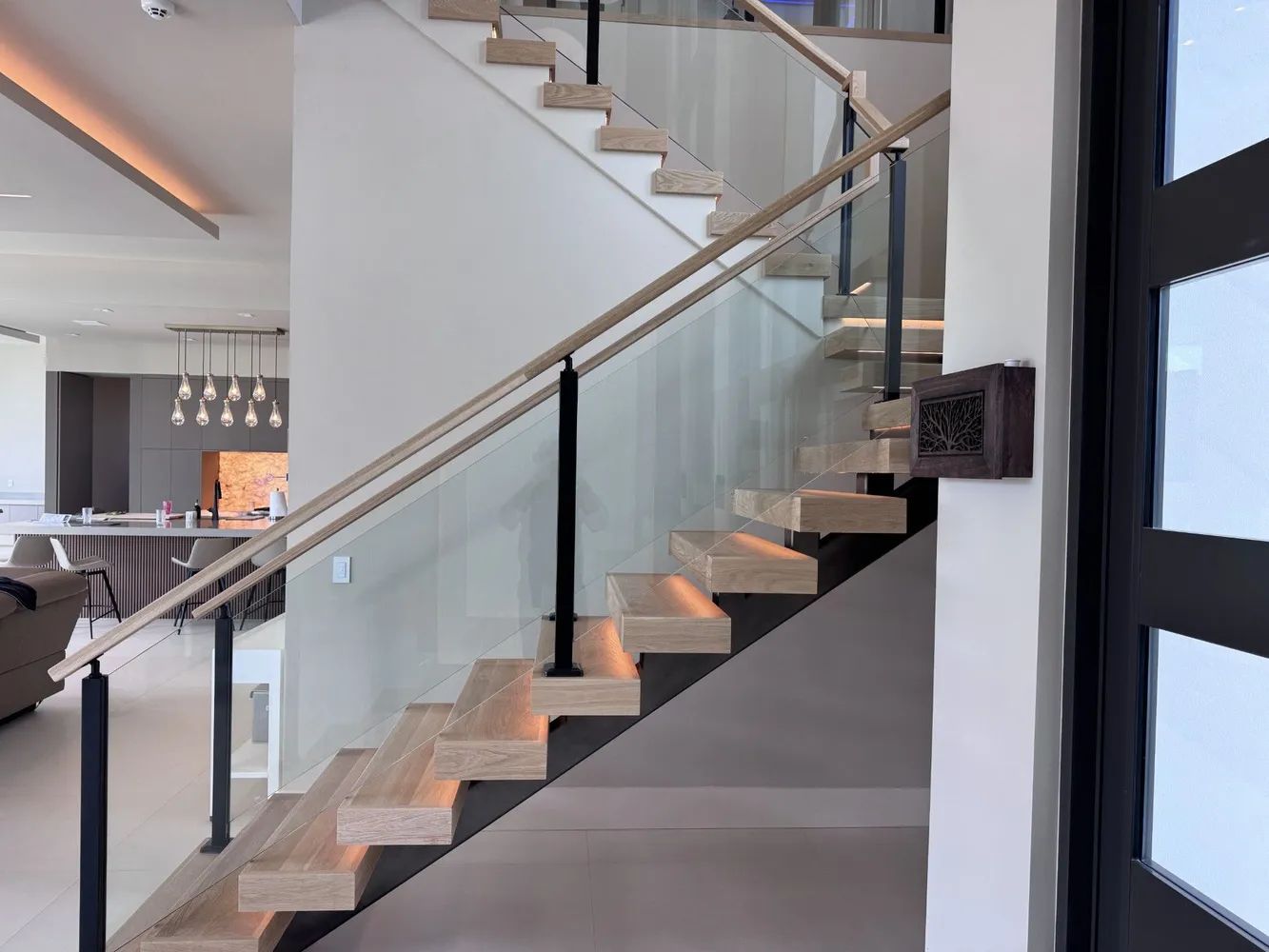 Modern staircase with wood steps, glass railing, and white walls in a contemporary home interior