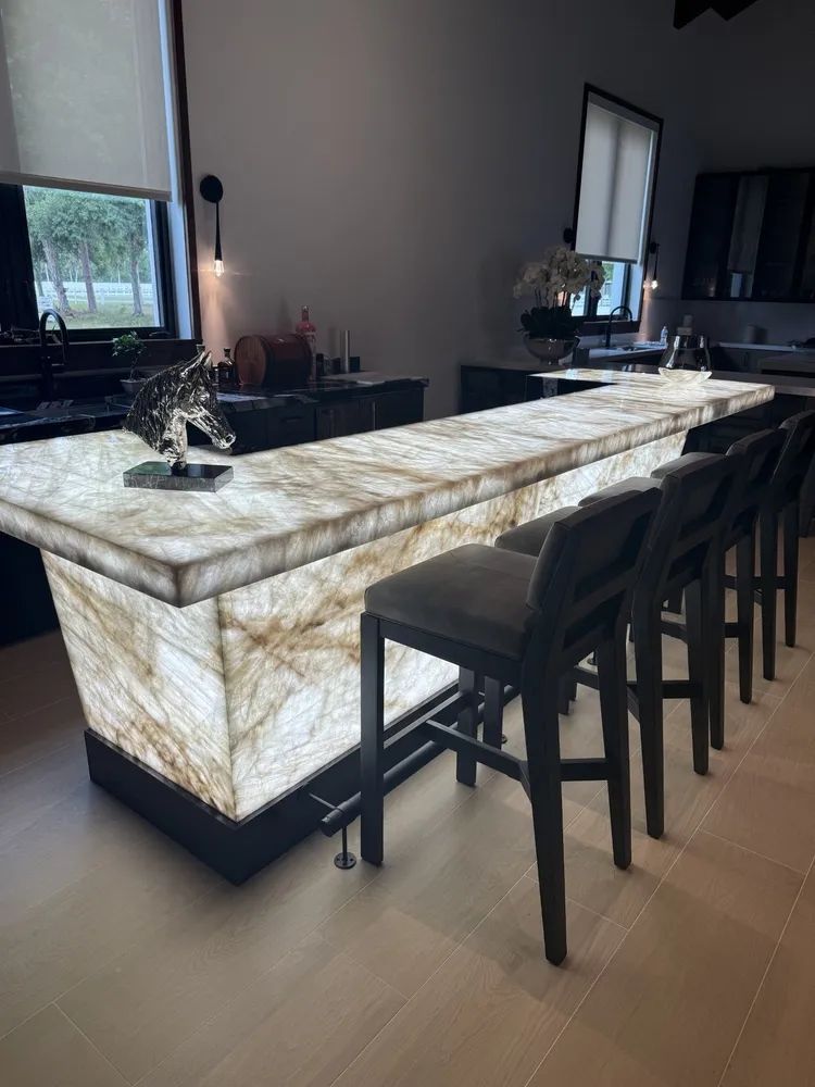 Marble-front bar counter with dark stools in a modern kitchen or lounge