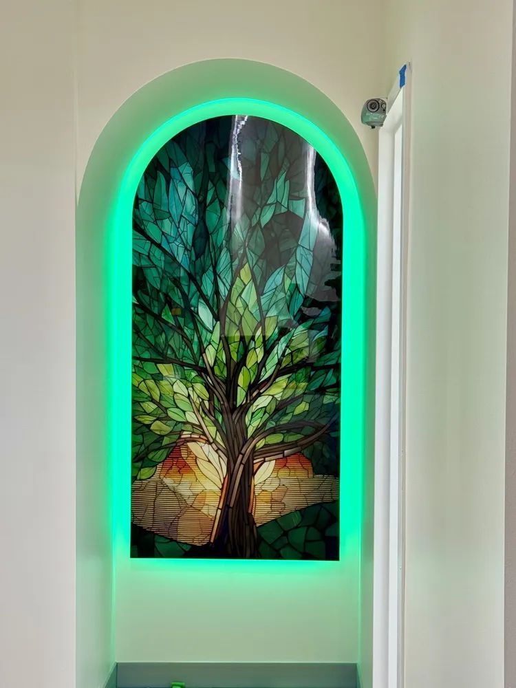 Illuminated arched wall niche with a stained-glass tree panel and green LED lighting