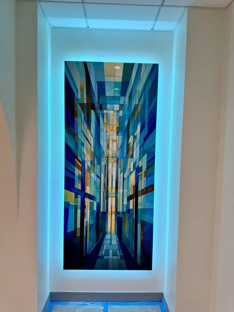 Abstract blue and gold vertical artwork in a white recessed wall niche, lit with cool blue lighting