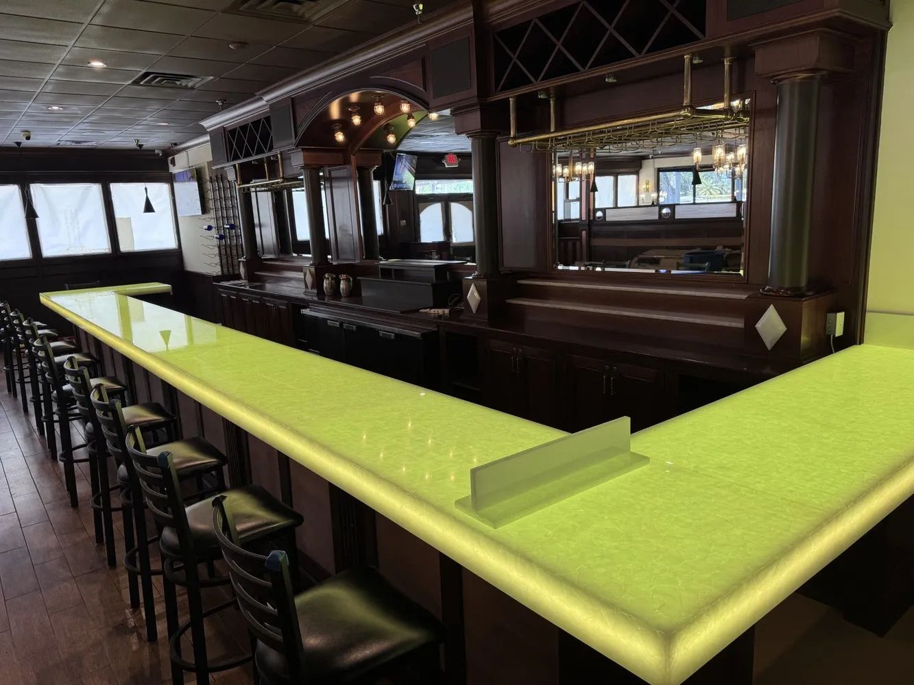 Long neon-green bar counter with stools in a dimly lit pub interior