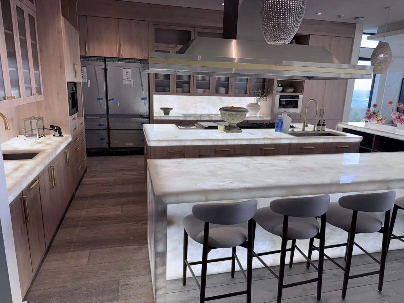 Modern kitchen with large island, bar stools, stainless fridge, and open shelving in a pink and white interior