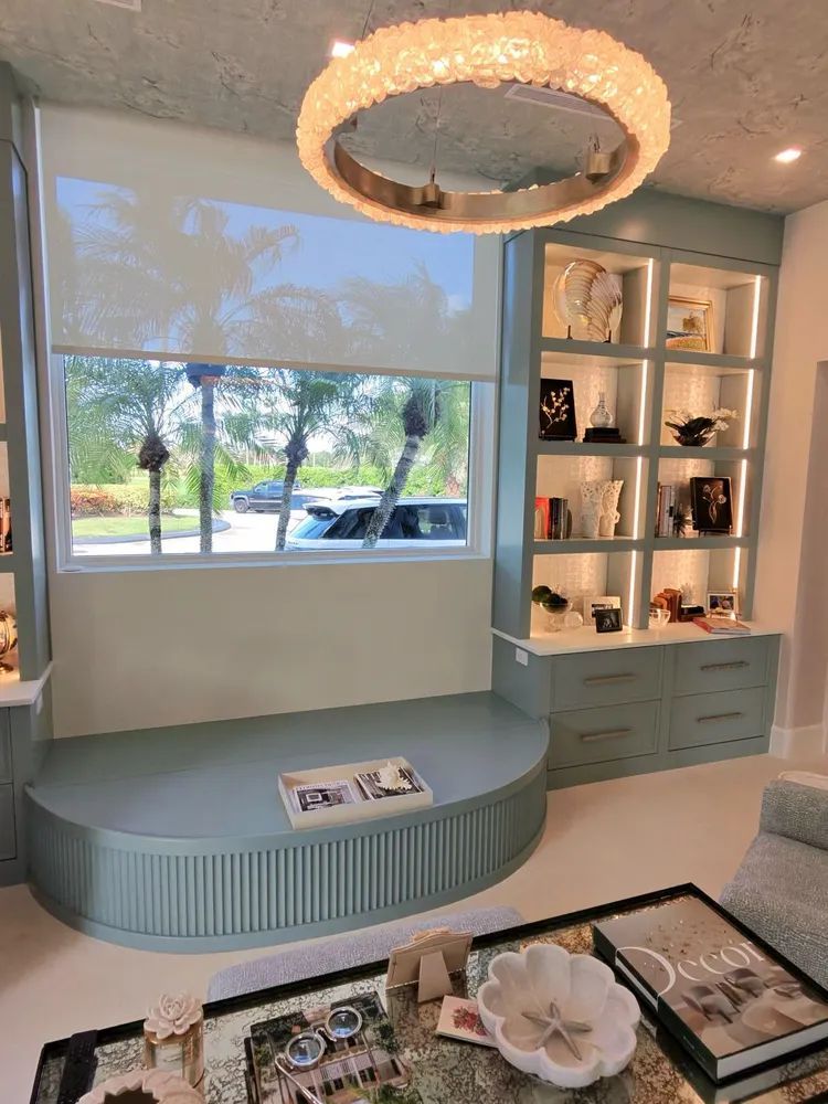 Modern living room with curved bench, built-in shelving, and large window overlooking greenery