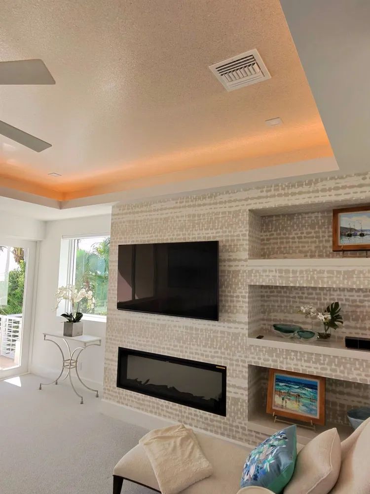 Modern living room with wall-mounted TV, fireplace, white brick shelves, and soft orange ceiling lighting