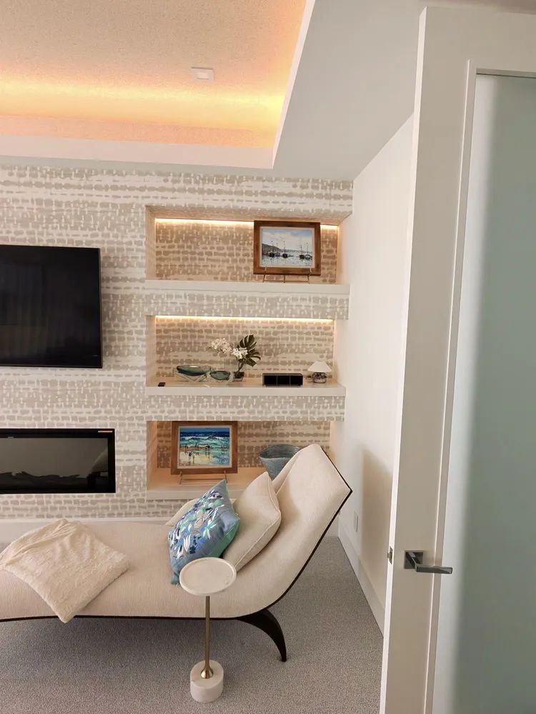 Modern living room with built-in shelves, TV, chaise lounge, and warm accent lighting.