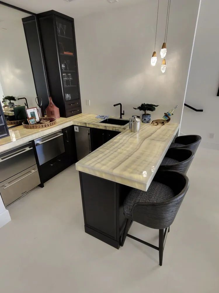 Modern kitchen with black cabinets, light wood island, pendant lights, and woven bar stools