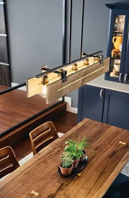 Dining room with wooden table, pendant light, and dark blue cabinets against gray walls.