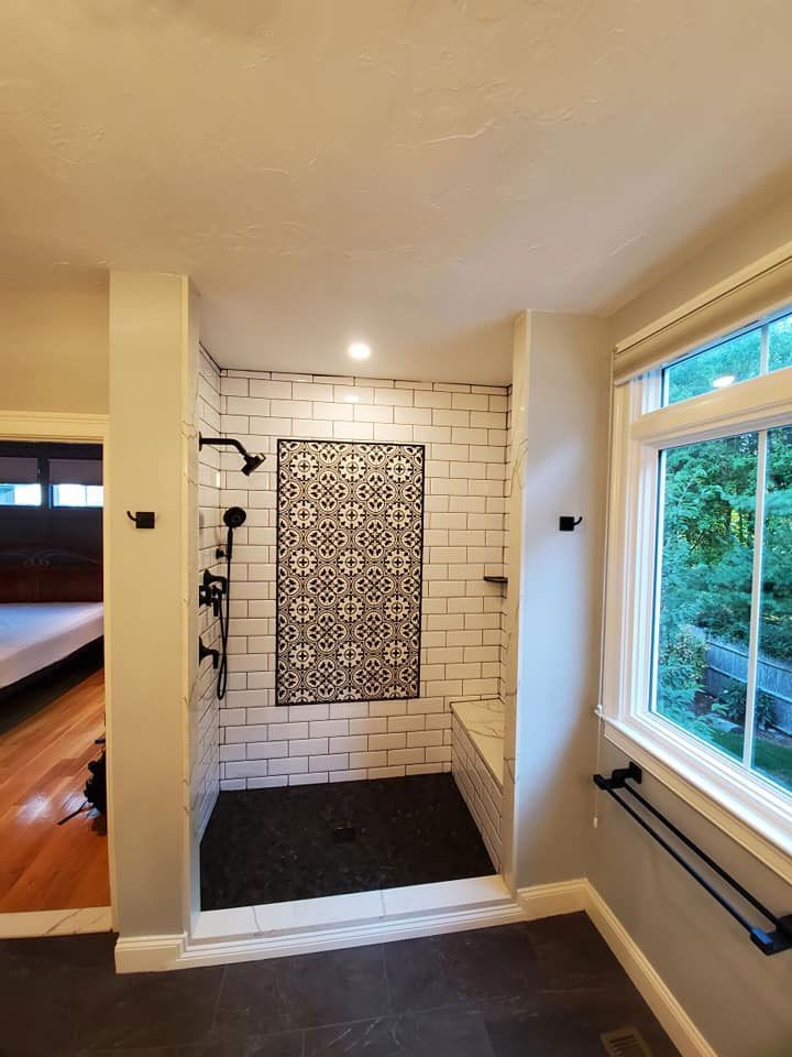 Bathroom with white subway tile shower, black accent tile, bench, and black fixtures.